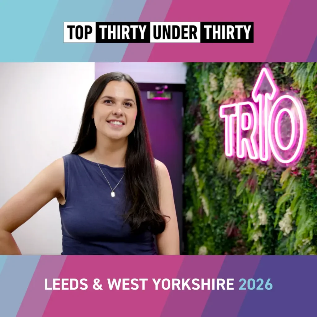 El Craig smiling in front of a pink neon ‘Trio’ branded sign as she is interviewed by the Hype3 video production team, recording her insights on the Top 30 Under 30 experience.