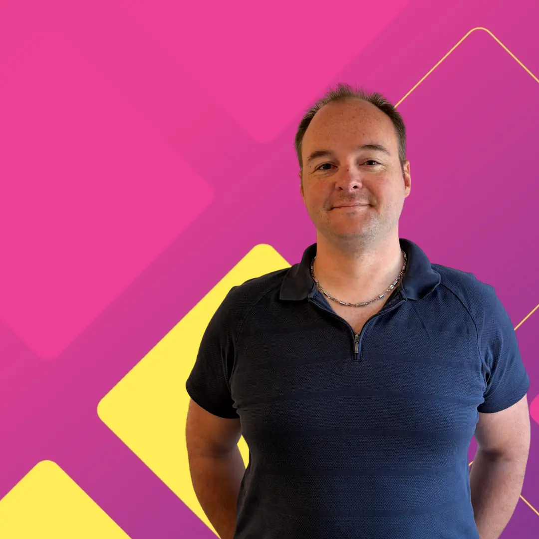 David in front of a pink background, in a blue shirt