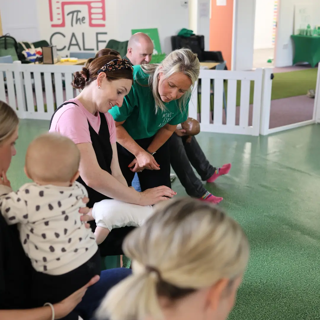 First aid trainer demonstrating first aid with a parent in classroom setting